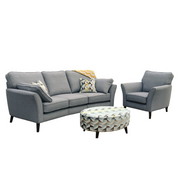 A stylish living room set featuring the Retro Angle seatee in gray, paired with a matching armchair, geometric-patterned round ottoman, and accent pillows—all elegantly displayed against a white backdrop.