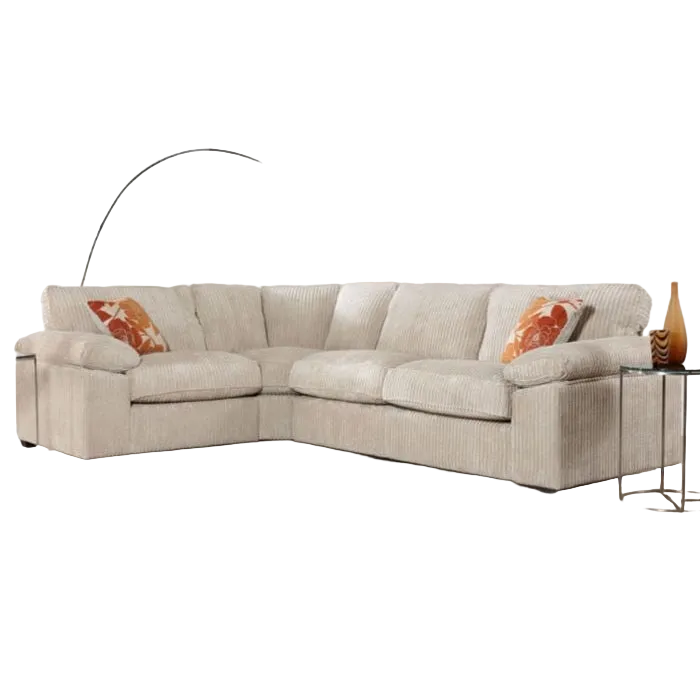 The Dexter Corner is a modern beige corduroy corner sofa, paired with two orange patterned throw pillows, a glass side table with a brown vase, and a curved floor lamp in the background.