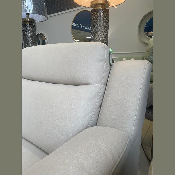 A close-up view of a Lorenzo Electric Recliner Sofa in a furniture store, with stylish lamps and round mirrors behind it. The store’s name, “Finlay’s Furniture,” appears reflected in the background.