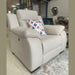 A large modern beige armchair with wide armrests and a colorful geometric pillow is showcased in a showroom, making it the ideal match for your Lorenzo Electric Recliner Sofas.