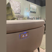 Close-up of the Chloe Electric Recliner’s taupe microfibre arm, featuring illuminated control buttons for easy electric reclining. In the background, a modern living room with wall art, green pillows, and a standing lamp enhances the stylish design of this contemporary sofa.