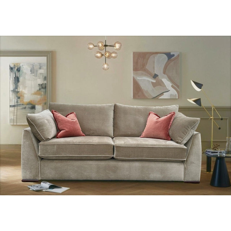 The Chantel Collection beige sofa by vendor-unknown, featuring aquaclean fabric and two pink pillows, sits in a modern living room with abstract wall art, a black floor lamp, round side table, magazine on wooden floor, and a contemporary chandelier overhead.