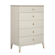 The Diletta Tall 5 Drawer Chest features a modern, light wood finish with ribbed design. The top drawer has a textured front, and all drawers have gold-colored handles and leg accents for an elegant touch.