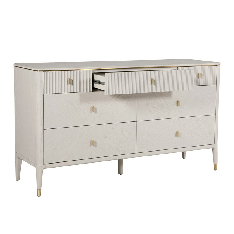 The Diletta Wide 7 Drawer Chest in white features gold-accented handles and legs, with six closed drawers and a partially open central upper drawer—making it a chic, modern storage solution for your bedroom.
