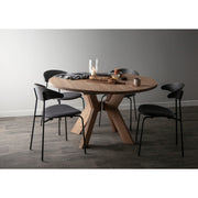 Dining table and chairs set with round top and unique X-shaped wooden base, decorated with a candle and food.