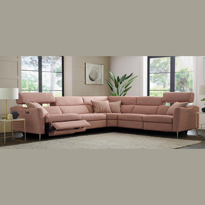 A modern living room with the Otis Range large pink sectional sofa featuring a Cloud Zero recliner and lumbar support, patterned cushions, a potted plant, floor-to-ceiling windows, abstract wall art, and light-toned decor.