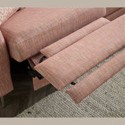 A close-up of the Otis Sofa Range in pink aquaclean fabric, featuring adjustable headrests and a reclining footrest, shown beside a textured beige rug on a wooden floor.