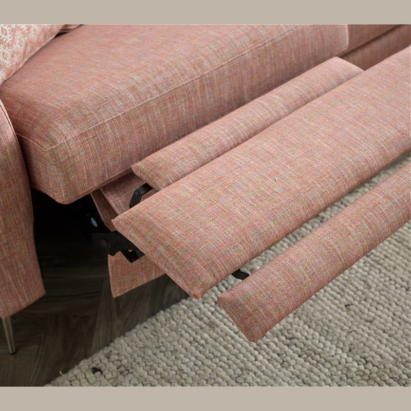 A close-up of the Otis Sofa Range in pink aquaclean fabric, featuring adjustable headrests and a reclining footrest, shown beside a textured beige rug on a wooden floor.