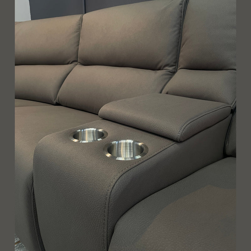 A close-up of the Vegas Corner Group, a modern gray corner sofa with wipeable fabric, stainless steel cup holders in the built-in armrest, set against a dark wall.
