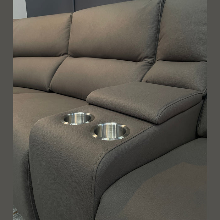 A close-up of the Vegas Corner Group, a modern gray corner sofa with wipeable fabric, stainless steel cup holders in the built-in armrest, set against a dark wall.