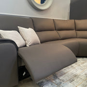 The Vegas Corner Group, a modern gray sofa with wipeable fabric and a built-in electric recliner, is paired with two light pillows, a floor lamp, round wall mirror, and patterned rug to create this cozy living room.