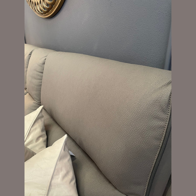 A close-up shows the light gray, textured backrest of the Vegas Corner Group sofa with two white pillows against it, set by a gray wall. A gold-framed mirror appears partially in the top left corner.