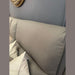 A close-up shows the light gray, textured backrest of the Vegas Corner Group sofa with two white pillows against it, set by a gray wall. A gold-framed mirror appears partially in the top left corner.
