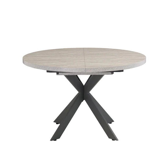 The Rimini Round Extending Table features a light wood top and black crossed metal legs, offering a modern, space-saving dining solution. Displayed against a plain white background.