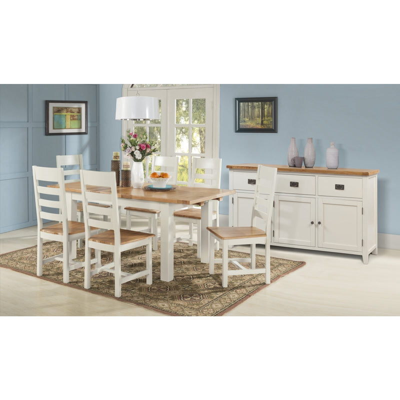 A dining room featuring the Skellig Dining Table & 4 Chairs by vendor-unknown, paired with a white sideboard, rug, and pendant lamp. Light blue walls display framed art and a window with a view of greenery.
