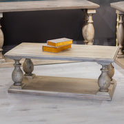 The Marwood Coffee Table, featuring turned legs and a lower shelf, stands on a light wood floor. Measuring 120 cm wide by 60 cm deep, it holds two closed decorative boxes and is surrounded by matching wooden furniture.