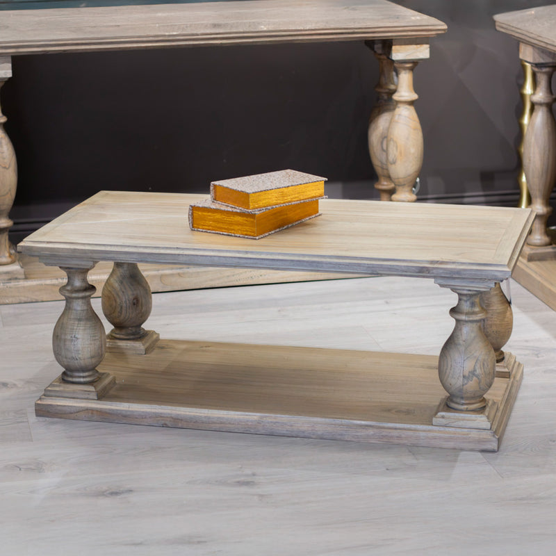 The Marwood Coffee Table, featuring turned legs and a lower shelf, stands on a light wood floor. Measuring 120 cm wide by 60 cm deep, it holds two closed decorative boxes and is surrounded by matching wooden furniture.