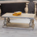 The Marwood Coffee Table, featuring turned legs and a lower shelf, stands on a light wood floor. Measuring 120 cm wide by 60 cm deep, it holds two closed decorative boxes and is surrounded by matching wooden furniture.