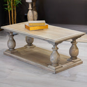 The Marwood Coffee Table, measuring 120 cm wide by 60 cm deep, features ornate turned legs, a lower shelf, and sits on a light wood floor with a decorative box on top and a plant in the background.