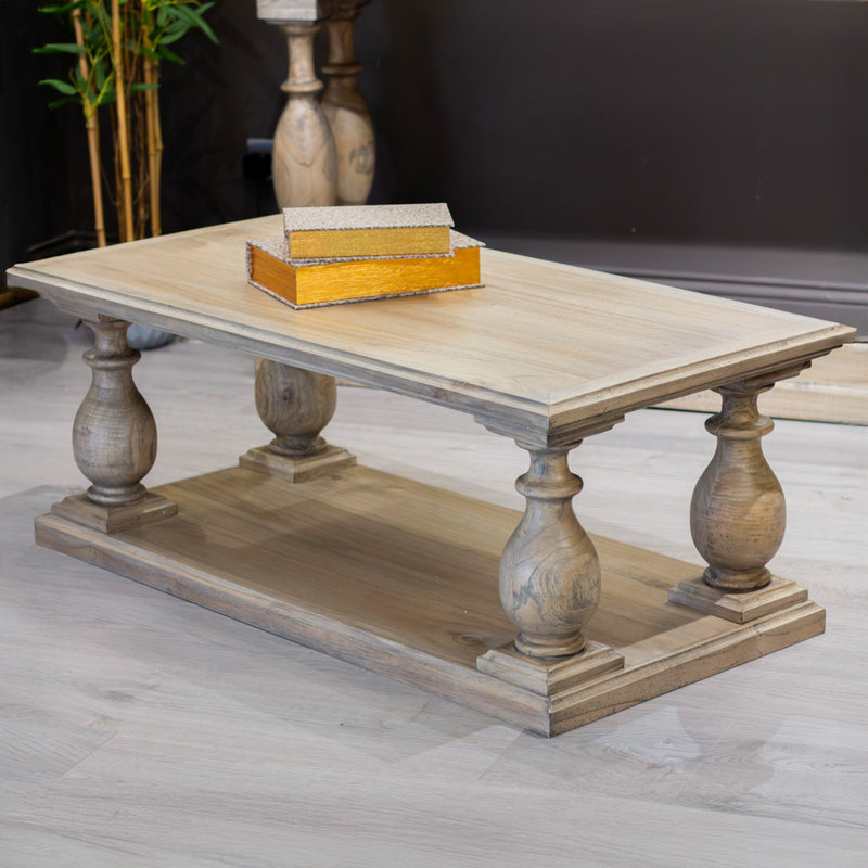 The Marwood Coffee Table, measuring 120 cm wide by 60 cm deep, features ornate turned legs, a lower shelf, and sits on a light wood floor with a decorative box on top and a plant in the background.