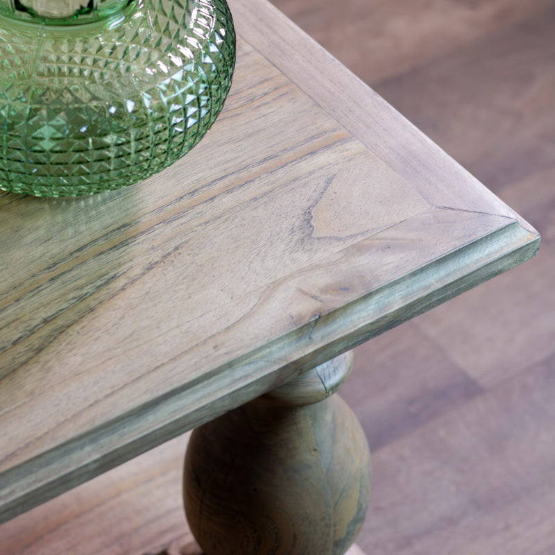 A close-up of the Marwood Coffee Table corner with a turned leg, topped with a green textured glass vase. Its natural wood finish highlights the grain and knots. Dimensions: 120 cm wide, 45 cm high.
