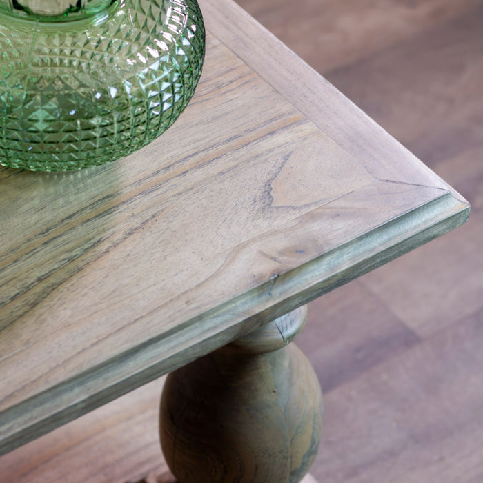 A close-up of the Marwood Coffee Table corner with a turned leg, topped with a green textured glass vase. Its natural wood finish highlights the grain and knots. Dimensions: 120 cm wide, 45 cm high.