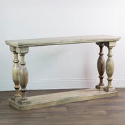The Marwood Large Console Table features a natural finish, rectangular top and bottom shelf, and four decorative turned legs. Measuring 150 cm wide and 82 cm high, it stands on a wooden floor against a plain white wall.