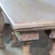 A close-up view of the Marwood Large Console Table’s corner showcases its smooth, light-colored surface and turned legs on a wooden floor; its elegant design features dimensions of 82 cm in height and 150 cm in width.