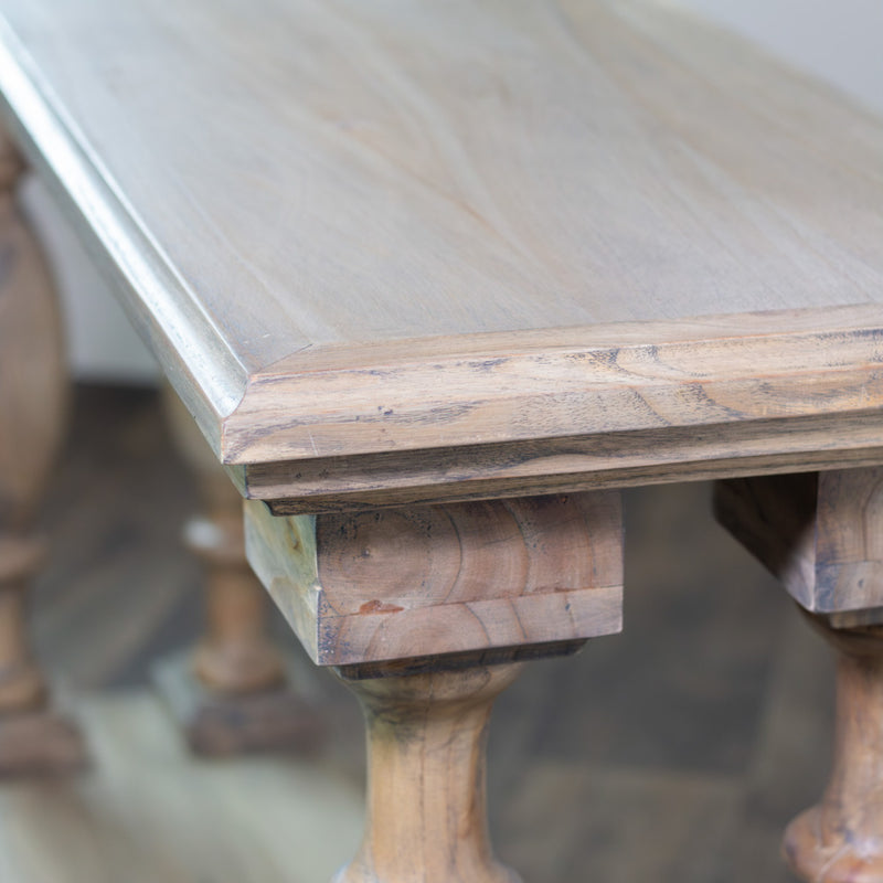 A close-up view of the Marwood Large Console Table’s corner showcases its smooth, light-colored surface and turned legs on a wooden floor; its elegant design features dimensions of 82 cm in height and 150 cm in width.