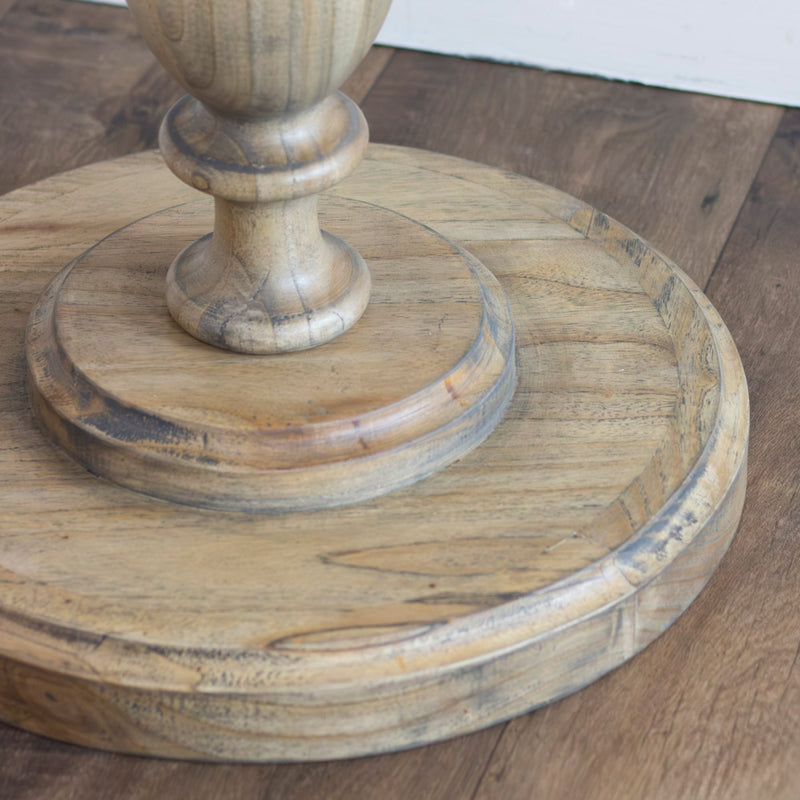 Close-up of the Marwood Round Side Table featuring a round, wooden pedestal base with natural wood grain and rustic finish, placed on a wooden floor. Dimensions: 50 cm wide, 57 cm high.