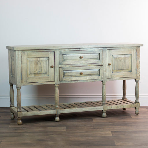 The Marwood Large Sideboard Console, measuring 82 cm high and 150 cm wide, has two drawers, two cabinets, a slatted lower shelf, and turned legs. It stands on a wood floor against a plain white wall.