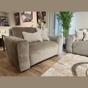 A modern living room featuring two Opus Swivel Cuddlers in plush gray Aquaclean fabric, decorative pillows, a beige patterned rug, potted green plant, and framed artwork. Wooden floors and natural light complete the contemporary look.