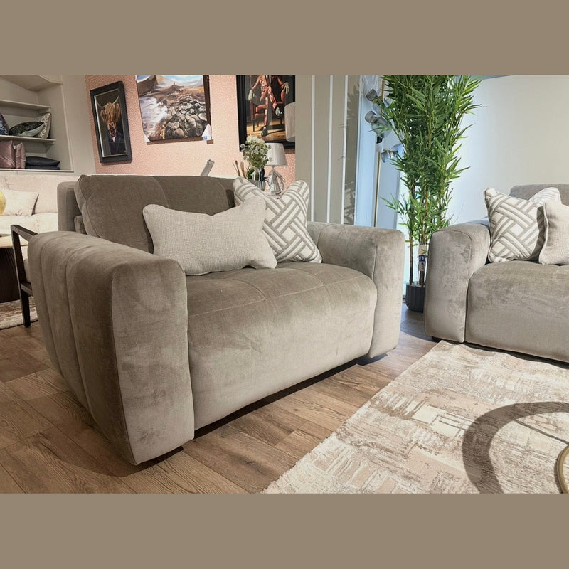 A modern living room featuring two Opus Swivel Cuddlers in plush gray Aquaclean fabric, decorative pillows, a beige patterned rug, potted green plant, and framed artwork. Wooden floors and natural light complete the contemporary look.