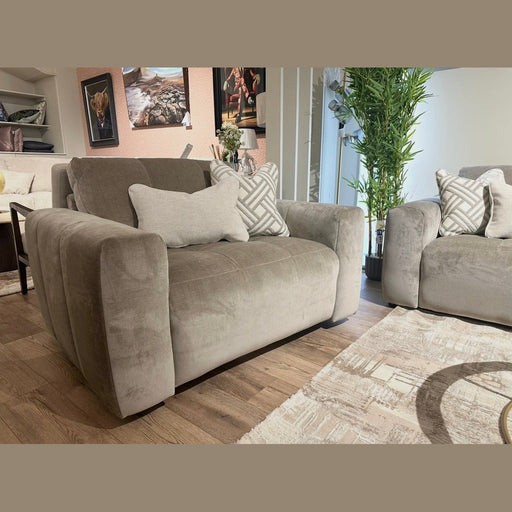 A modern living room featuring two Opus Swivel Cuddlers in plush gray Aquaclean fabric, decorative pillows, a beige patterned rug, potted green plant, and framed artwork. Wooden floors and natural light complete the contemporary look.