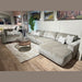 A modern living room with the Opus Swivel Cuddler in light gray, matching armchair, white and patterned pillows, a round wooden coffee table, beige rug, and landscape paintings on the wall.