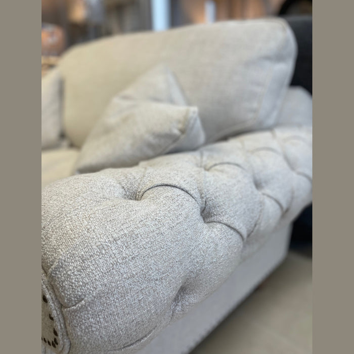 A close-up of the Keaton sofa, featuring light beige tufted design with fibre-filled seats and matching pillows, showcased in a softly lit room.