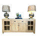 The Le Manoir Sideboard in light wood features two glass-front cabinets, two drawers, and a center cabinet. Silver lamps with beige shades flank a tray with a floral arrangement and candles on top.