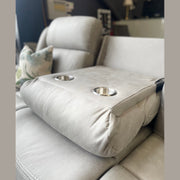 A close-up of the light gray Reno Recliner Sofa armrest with two built-in cup holders. A botanical-pattern pillow in the background highlights the stylish comfort and washable fabric of this 3 seater.