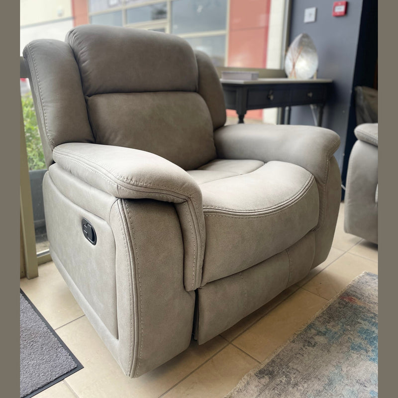 A light gray Reno Recliner Sofa with washable fabric and padded armrests sits on a tiled floor in a modern room with large windows and contemporary furniture in the background.