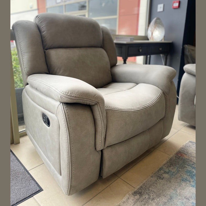 A light gray Reno Recliner Sofa with washable fabric and padded armrests sits on a tiled floor in a modern room with large windows and contemporary furniture in the background.