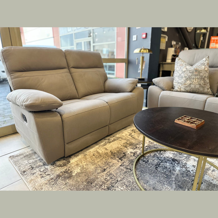 A modern living room featuring the Jude Recliner in washable microfiber, a matching armchair with a patterned cushion, a round black coffee table, and a decorative rug, arranged by large windows.
