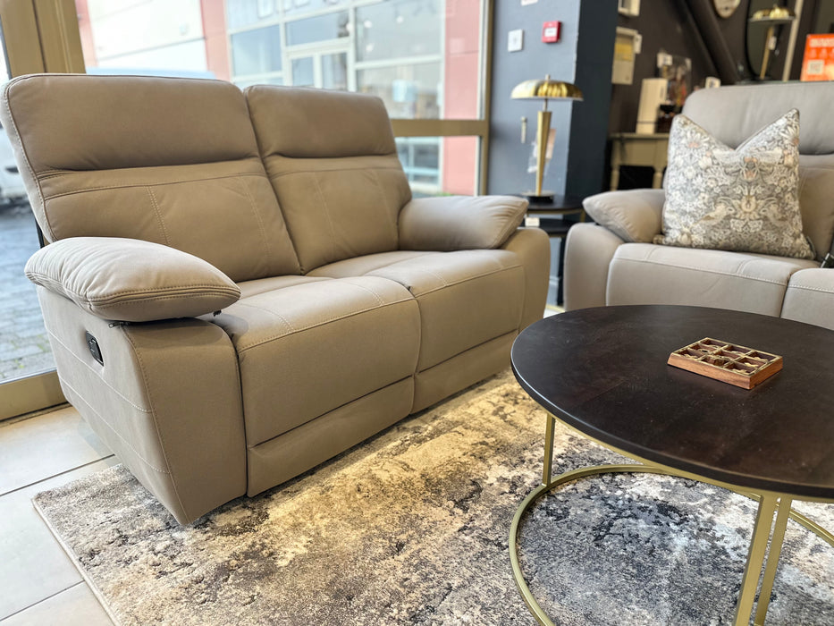 A modern living room featuring the Jude Recliner in washable microfiber, a matching armchair with a patterned cushion, a round black coffee table, and a decorative rug, arranged by large windows.
