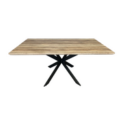 The Elson 1.6 Dining Table is a square wooden table with a light brown natural finish and a modern black metal pedestal base featuring bold X-shaped legs.