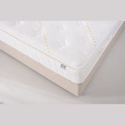 Close-up of the King Koil - Spinal Pocket Pillow Top, a white quilted mattress with subtle pattern and stitched detailing on a light beige bed base. Features a small side label and offers excellent support.
