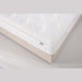 Close-up of the King Koil - Spinal Pocket Pillow Top, a white quilted mattress with subtle pattern and stitched detailing on a light beige bed base. Features a small side label and offers excellent support.