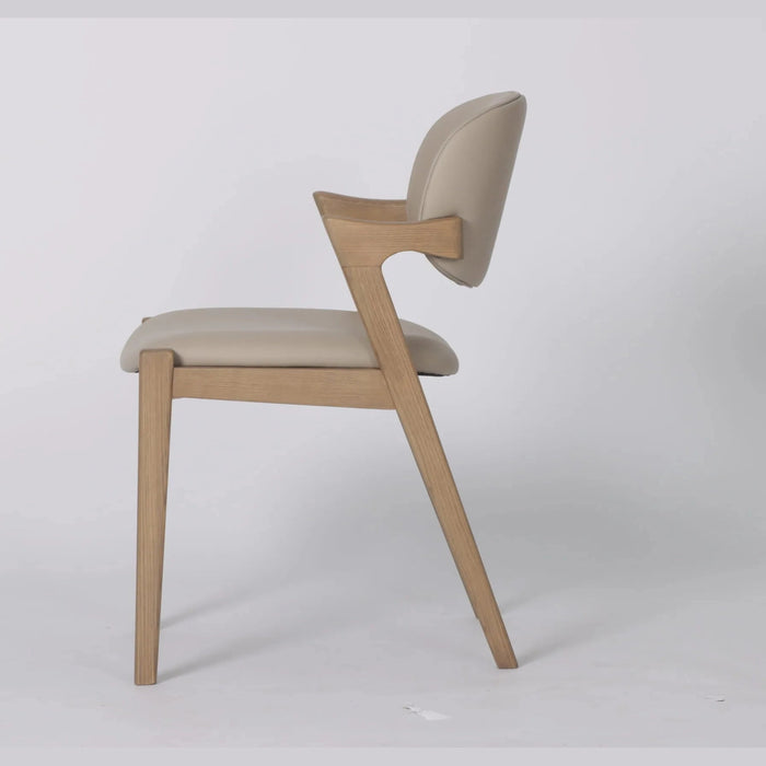 The Mila Beige PU Dining Chair is a modern chair with a solid wood frame and light beige PU cushioned seat and backrest, shown in profile against a white background. It features clean, angular lines and minimalist design.