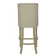 The Millie Counter Stool features a beige, easy-clean leatherette with a quilted diamond backrest and light wooden legs, shown from the rear—ideal for modern dining spaces.