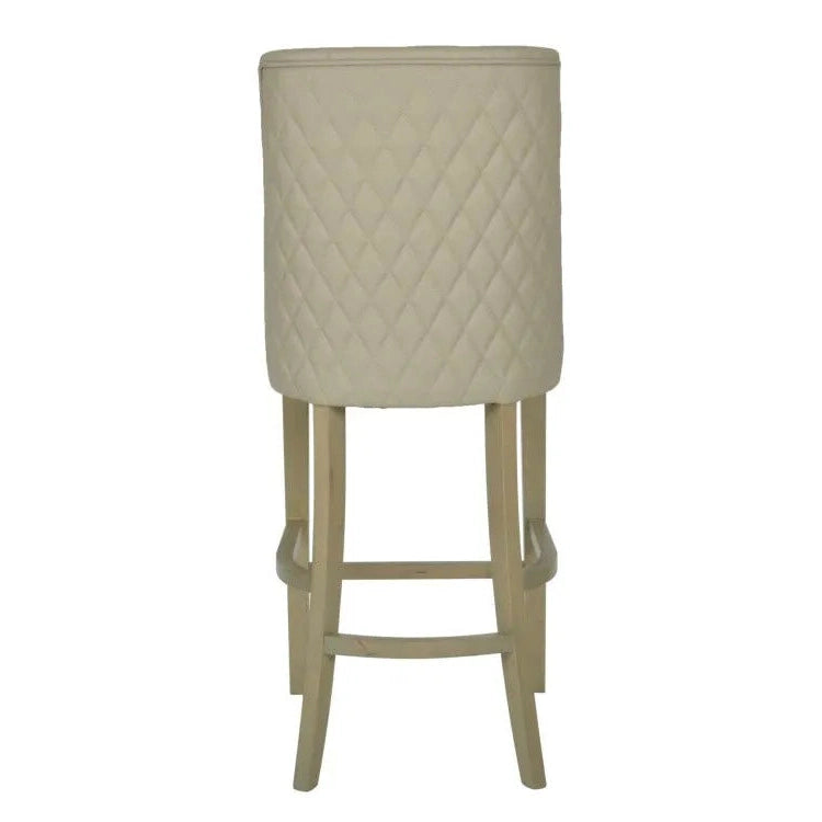 The Millie Counter Stool features a beige, easy-clean leatherette with a quilted diamond backrest and light wooden legs, shown from the rear—ideal for modern dining spaces.