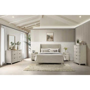 Modern bedroom featuring the Parma Bedframe with taupe fabric headboard, light gray upholstery, matching nightstands and dressers, beige rug, wall art above the bed, plants, décor accents, light wood floors, and vaulted ceiling with beams.