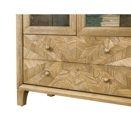 Close-up of the Solstice Display Cabinet, featuring solid wood construction, intricate chevron veneer on drawer fronts, four round metal knobs, and a natural wood grain finish.